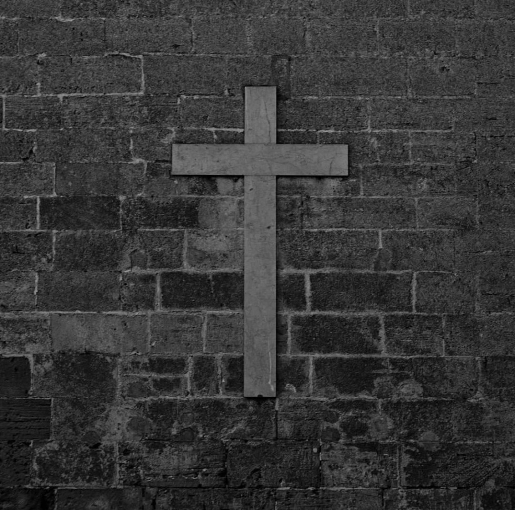A black and white cross on a brick exterior wall of a church in Mallorca Spain